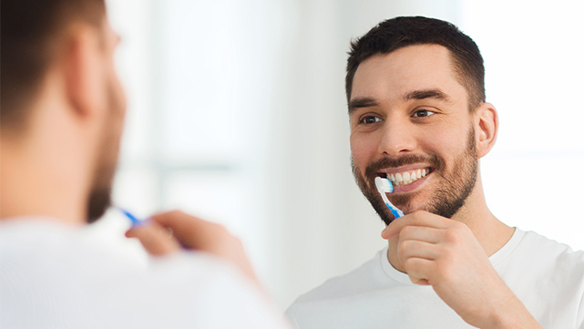 Homme sourit en se brossant les dents